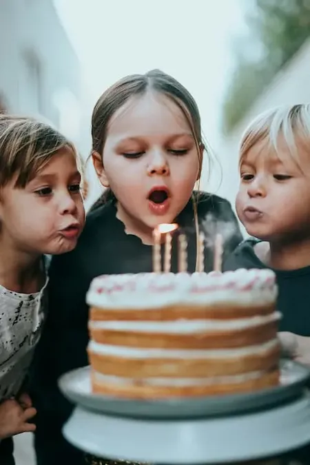 Trois enfants soufflant les bougies d'un gâteau d'anniversaire, symbolisant le souffle retrouvé grâce à l'arrêt du tabac.